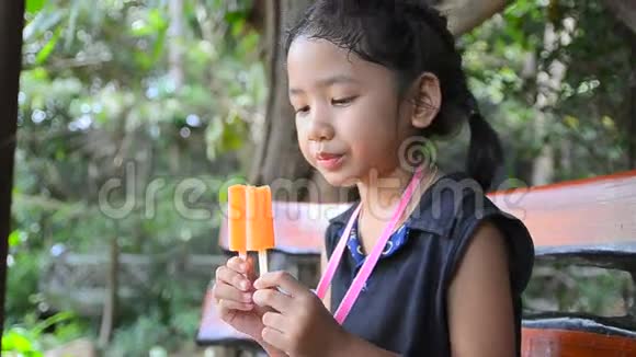 特写镜头可爱快乐的亚洲小女孩拿着橙色冰淇淋视频的预览图