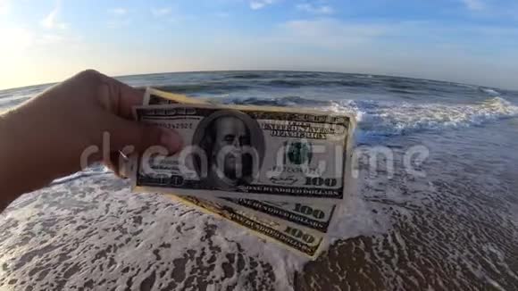 在海浪背景下拿着300美元钞票的女孩视频的预览图