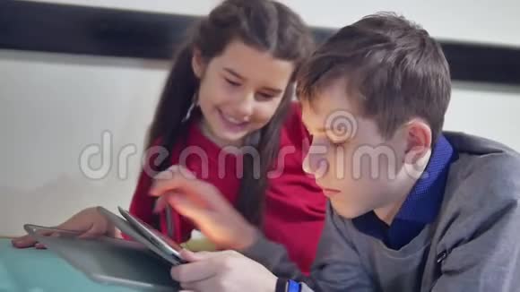 男孩和女孩在室内玩平板电脑兄妹儿童社交媒体在线游戏平板电脑视频的预览图