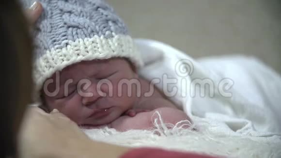 带着蓝色帽子的婴儿躺在白色毯子上视频的预览图
