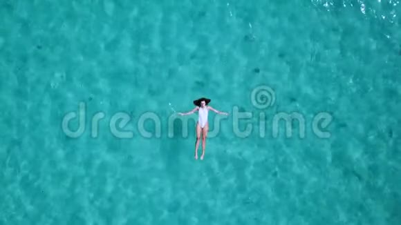 空中观景美丽的年轻女子穿着白色比基尼漂浮在水面上晶莹剔透碧绿色的海洋视频的预览图