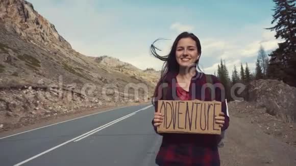 少年女孩在山路上举着冒险标志笑着笑着徒步旅行寻找冒险视频的预览图