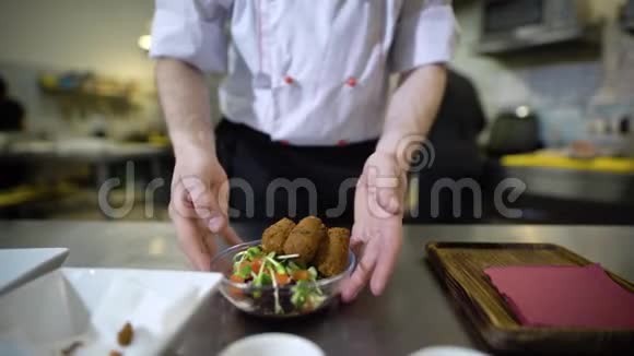 餐厅厨房里的厨师穿着白色西装在托盘上收集零食酱汁和沙拉一个美丽的视频的预览图