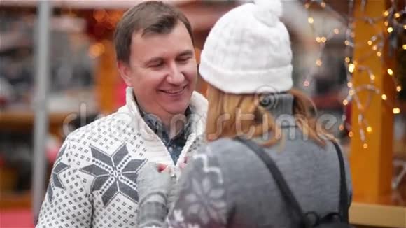 夫妻在圣诞节市场度过了一段有趣的时光男人笑着和一个女人说话幸福的年轻家庭祝你快乐视频的预览图