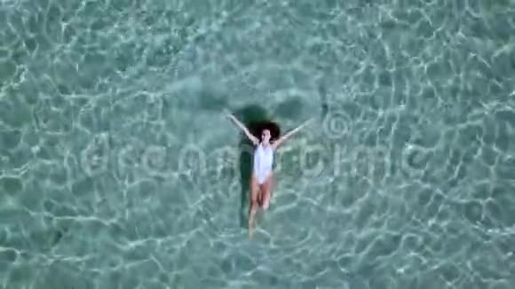 空中观景美丽的年轻女子穿着白色比基尼漂浮在水面上晶莹剔透碧绿色的海洋视频的预览图