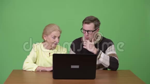 高级女商人和年轻帅哥一起使用笔记本电脑视频的预览图