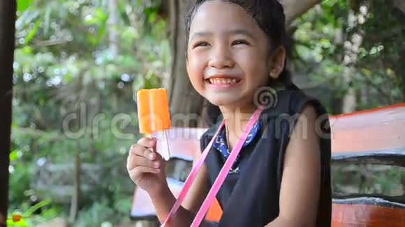 特写镜头可爱快乐的亚洲小女孩拿着橙色冰淇淋视频的预览图