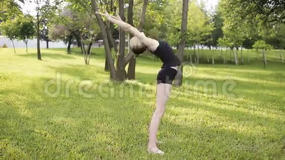 草地上公园里的健美操一个年轻的体操运动员视频的预览图