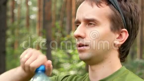 年轻的男性自行车运动员从瓶子里喝水绿色T恤特写视频的预览图