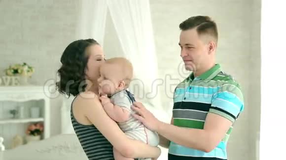 妈妈爸爸和6个月大的宝宝幸福的家庭和一个孩子玩父母双手抱着孩子看着相机视频的预览图