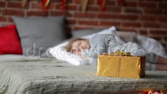 可爱的女孩睡在床上圣诞礼物站在她身边然后孩子醒来拿走你的礼物圣诞节视频的预览图