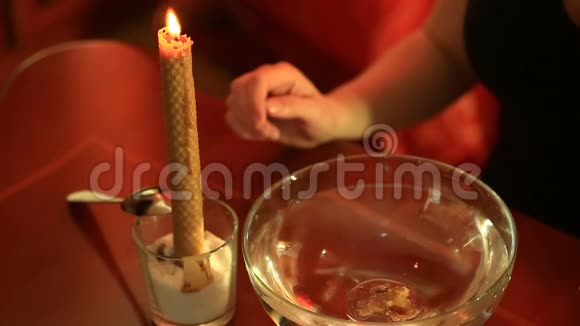 用蜡烛猜女人往水里倒蜡冷却蜡浮在透明的水碗里视频的预览图