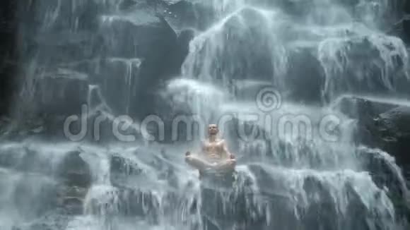 男子坐在瑜伽姿势的背景瀑布视频的预览图