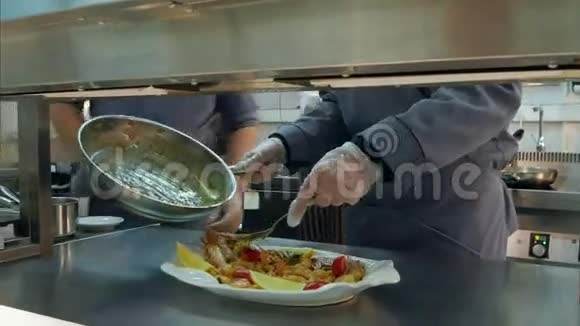 厨师他的男性手把煮熟的虾和蔬菜放在盘子里配上酱汁视频的预览图