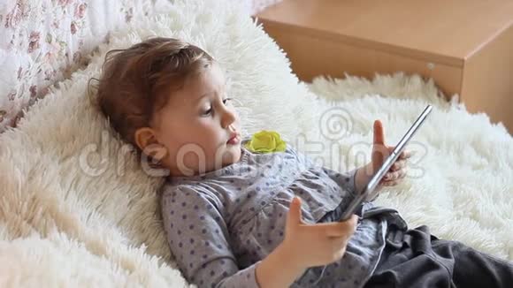 有趣的孩子手里拿着平板电脑在网上看动画片视频的预览图