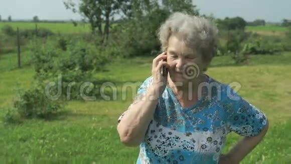 80多岁的老妇人在户外的智能手机上讲话视频的预览图