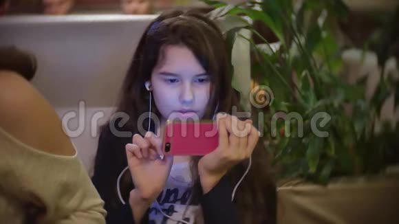 坐在快餐店里听智能手机音乐的少女女婴在咖啡馆里吃披萨视频的预览图