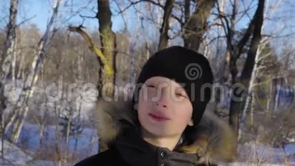 一个十几岁男孩的特写那男孩做了一张严肃的脸阳光明媚的冬天晚上在森林里视频的预览图