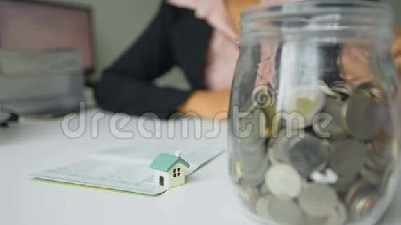 女人把硬币放进玻璃罐概念省钱买房子选择重点是房子视频的预览图