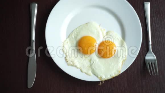 木桌上放煎蛋的白盘提供早餐鸡蛋视频的预览图