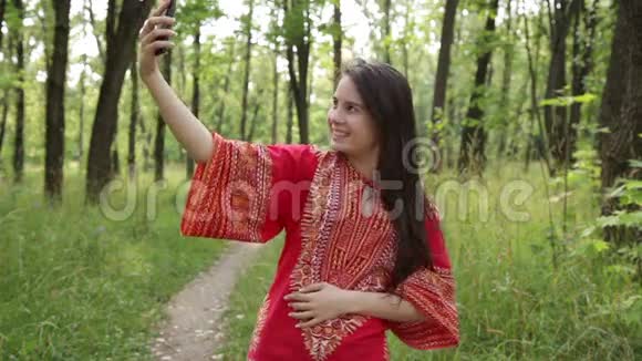穿红色衬衫的女人在公园里自拍视频的预览图
