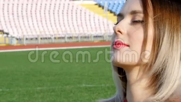 坐在足球场中央的女孩眨着眼睛视频的预览图