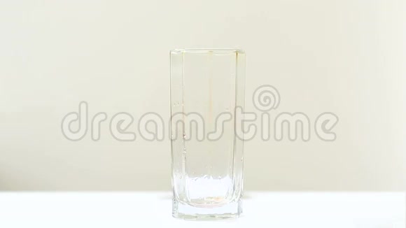 有人把果汁倒入玻璃杯中在白色背景下隔离的特写镜头视频的预览图