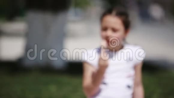 在阳光明媚的夏日可爱的小女孩在公园里吃冰淇淋视频的预览图