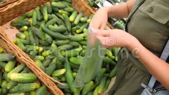 一个女人在蔬菜货架上的超市里买蔬菜和水果男人选择黄瓜慢动作4k视频的预览图