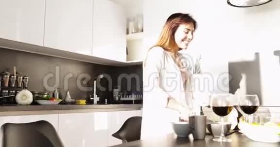 亚洲女人烹饪早餐厨房内部年轻快乐微笑女孩切割蔬菜晨曦视频的预览图