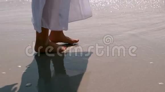 轻松的女人在潮湿的沙子上行走视频的预览图