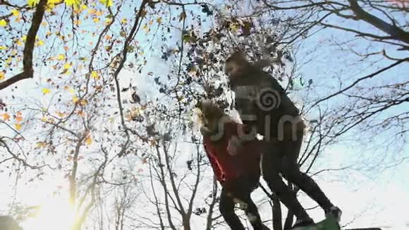 女孩从低角度射击扔树叶从长凳上跳下来视频的预览图