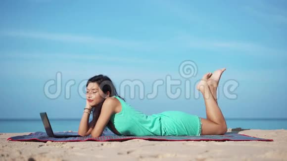 有笔记本电脑的漂亮女人在海滩上放松视频的预览图