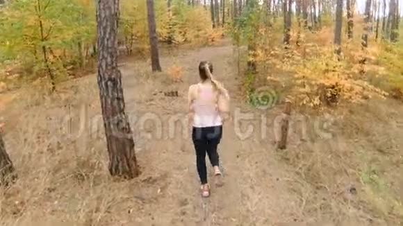 女性在森林中奔跑的慢速后视镜头视频的预览图