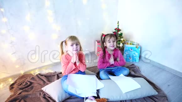 小女孩笑着说话摆姿势躺在地板上枕头靠墙里面放着花环和圣诞树视频的预览图