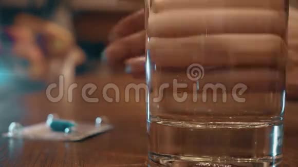 注意力不集中的女人手吃蓝色药丸和一杯水4K特写视频视频的预览图