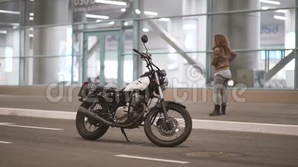 美丽的年轻女子骑着一辆古老的咖啡馆赛车摩托车在街上夜城女自行车手视频的预览图