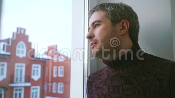 穿着毛衣的帅哥透过窗户微笑着视频的预览图
