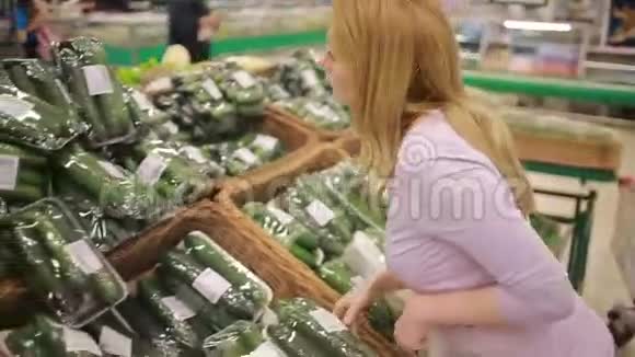 一个女人在超市的蔬菜货架上买蔬菜黄瓜视频的预览图