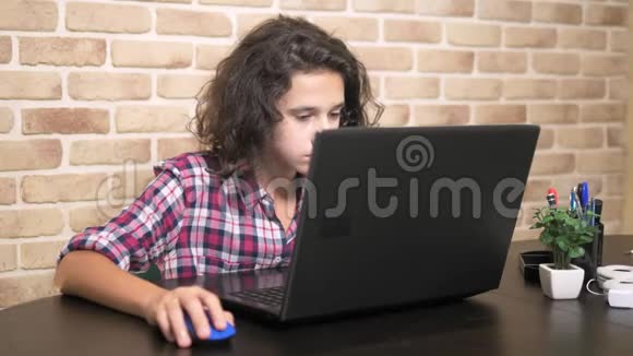 在笔记本电脑上工作在键盘上打字现代少年一个穿格子衬衫的卷发少年用的是视频的预览图
