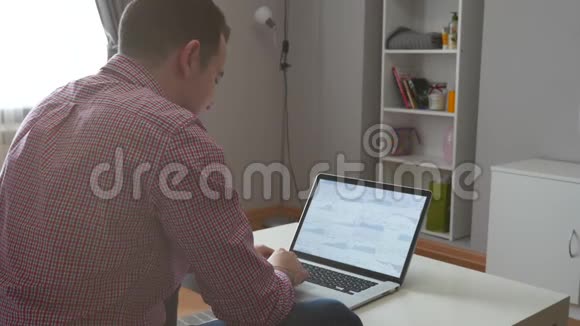 在家工作的人使用顶部和触控板年轻的商人坐在桌子上喝咖啡做工作视频的预览图