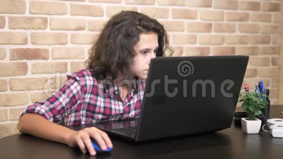 在笔记本电脑上工作在键盘上打字现代少年一个穿格子衬衫的卷发少年用的是视频的预览图