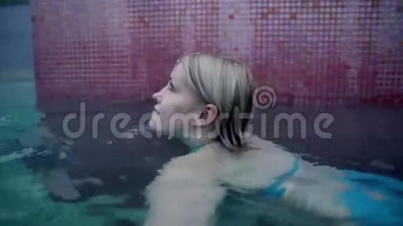 穿蓝色比基尼的年轻女子在下雪时在室外游泳池游泳视频的预览图
