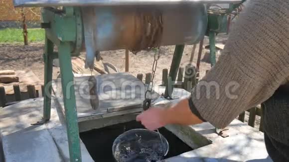 男人把链子和水桶一起丢进乡间的井里取水视频的预览图