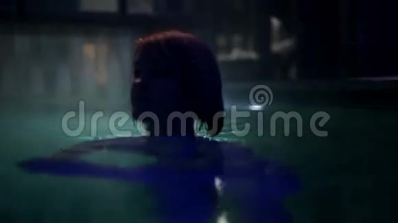 穿着蓝色比基尼的年轻女子游过相机在室外游泳池里尽情享受视频的预览图