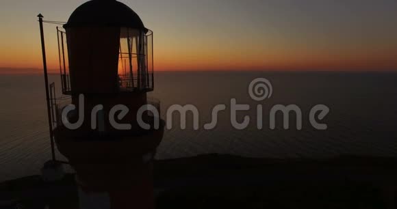 夏天在海边日落的背景下建造旧灯塔日落时分无人机飞过灯塔视频的预览图