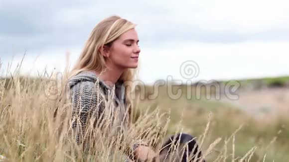 电影中在沙丘上放松的金发女人视频的预览图