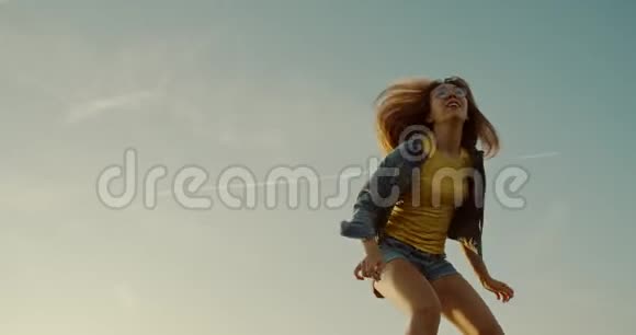 日落时分女孩在沙漠中的沙滩上跳跃视频的预览图