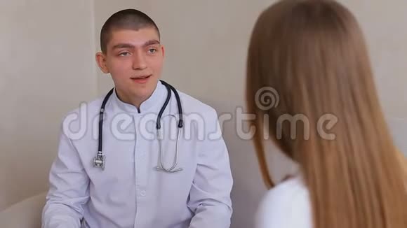 男医生为坐在灰色沙发背景下的医务室接待处的女孩提供指导和建议视频的预览图