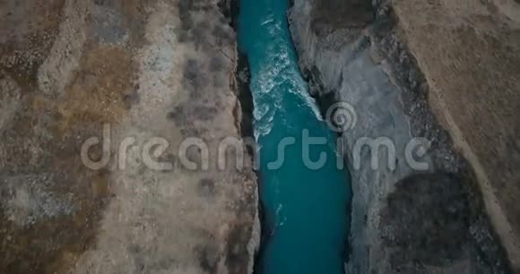 鸟瞰瀑布在缝隙中的海鸥飞越山谷的直升机和冰岛河流的湍流视频的预览图